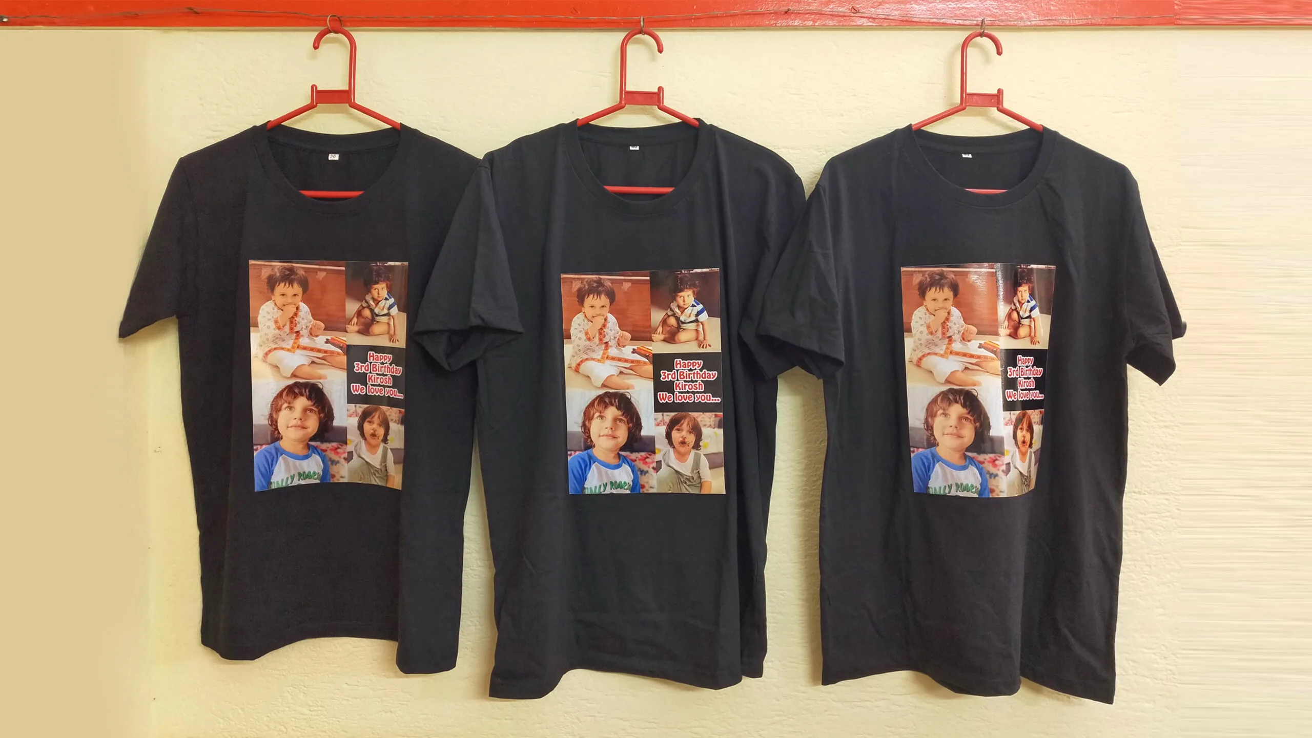 Three black T-shirts with a custom printed birthday photo collage of a young child named Kirosh, with the message “Happy 3rd Birthday Kirosh, We love you…”