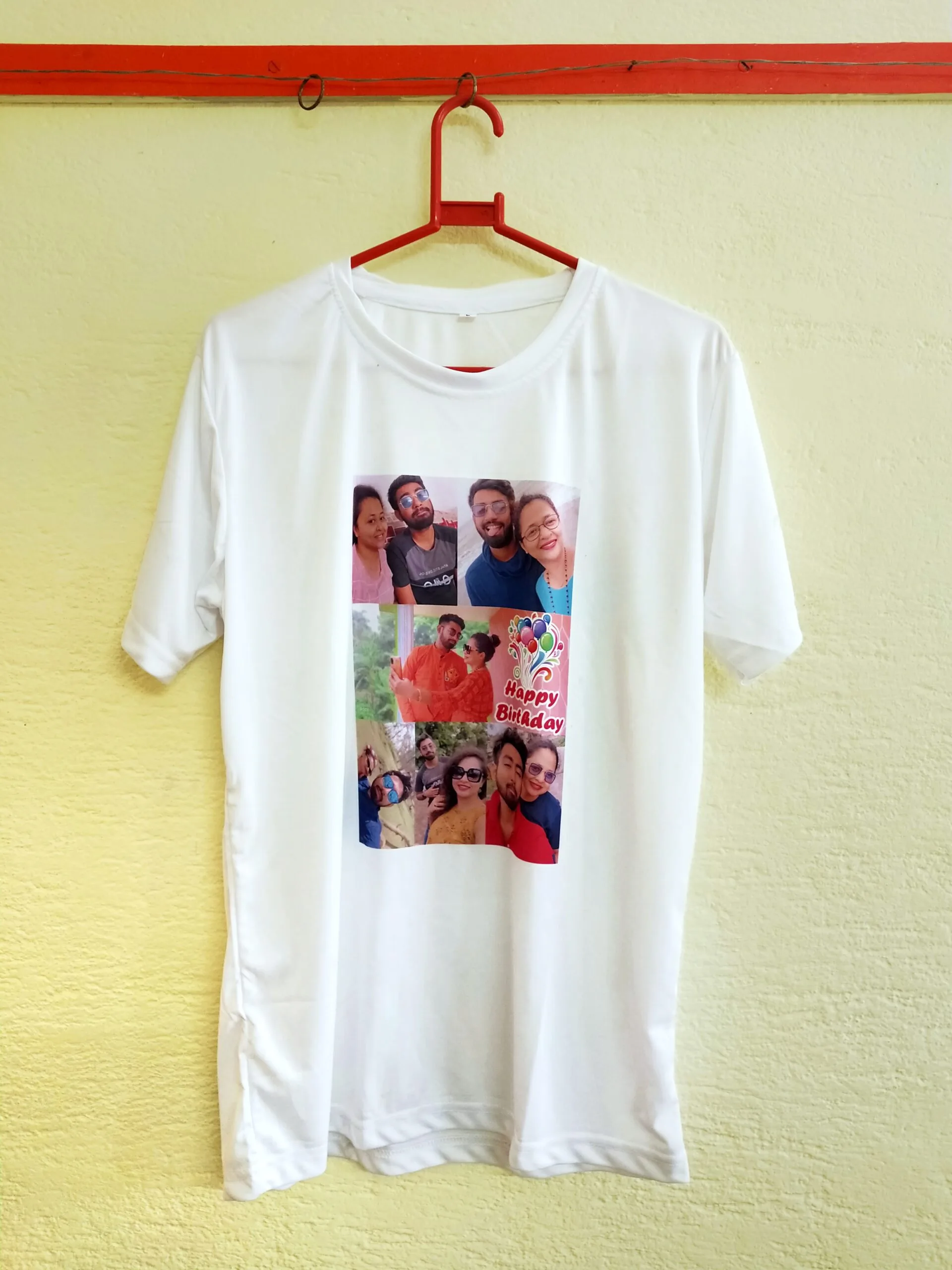 Custom white T-shirt with a birthday collage print featuring group selfies and “Happy Birthday” text, hanging on a red hanger.