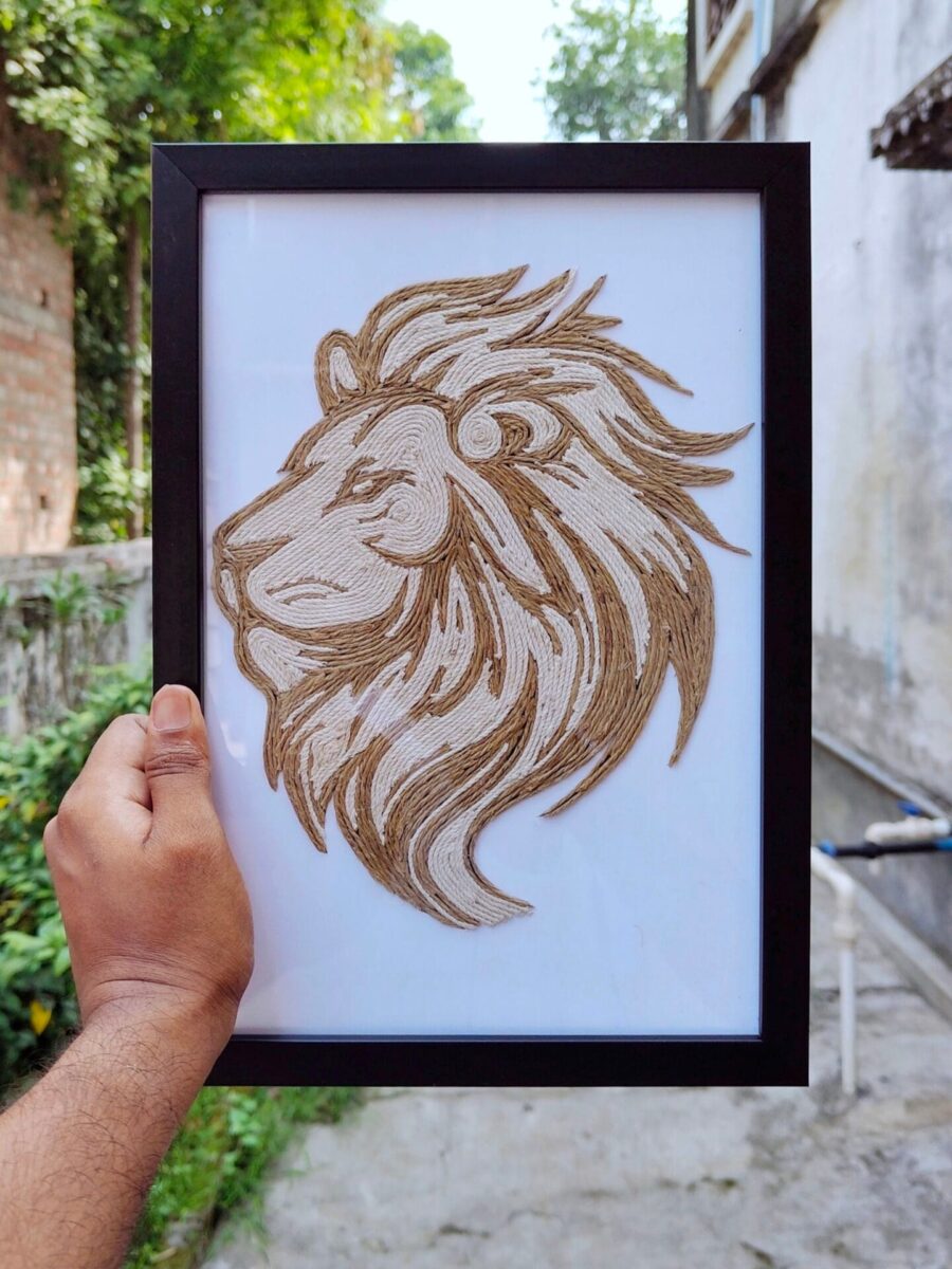 Hand holding a framed rope art of a majestic lion head, crafted with dual-tone jute threads on a white background.