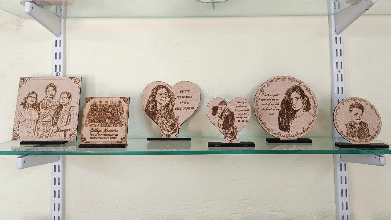 A collection of personalized engraved wooden photo plaques in square, heart, and round shapes, displayed on a glass shelf with messages and portraits.