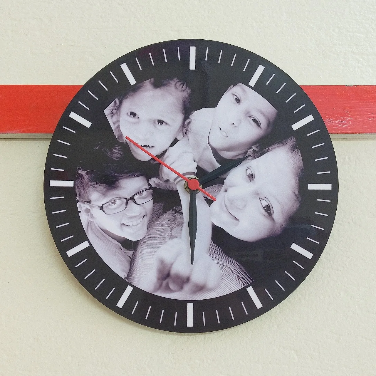 Personalized round wall clock with a black-and-white family photo printed on the dial, featuring minimalist white markers and red-black hands.