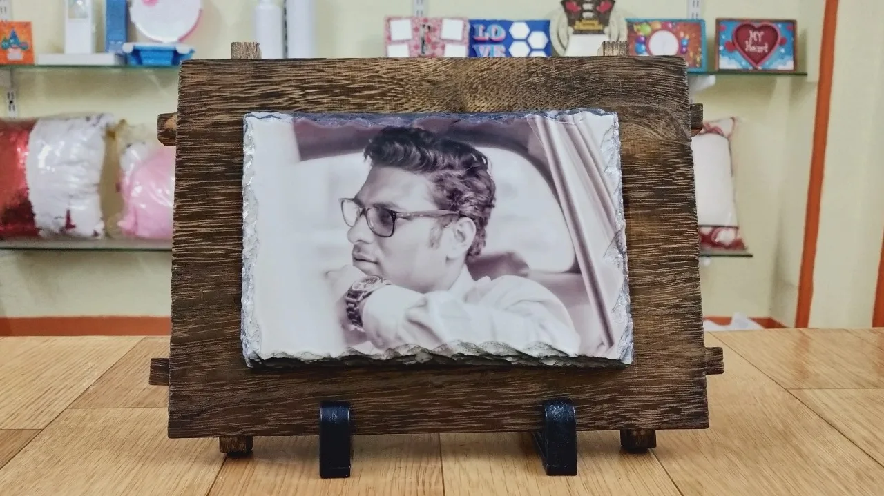 Personalized stone photo frame featuring a sepia-toned portrait of a man, mounted on a rustic wooden stand with a stylish display setup.