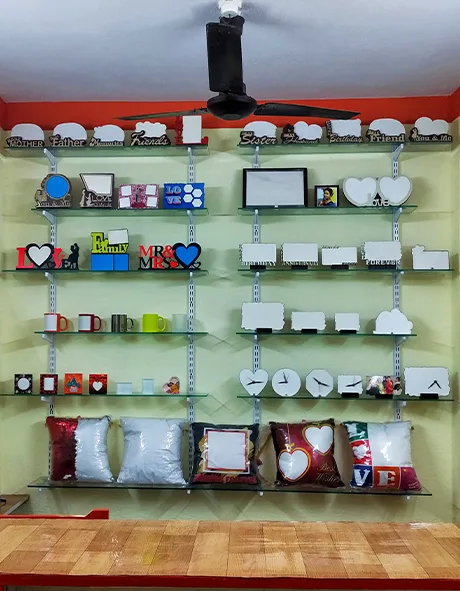 Wall-mounted display shelves in a gift store showcasing various blank customizable products including photo frames, clocks, mugs, pillows, wooden cutouts, and printed blocks.