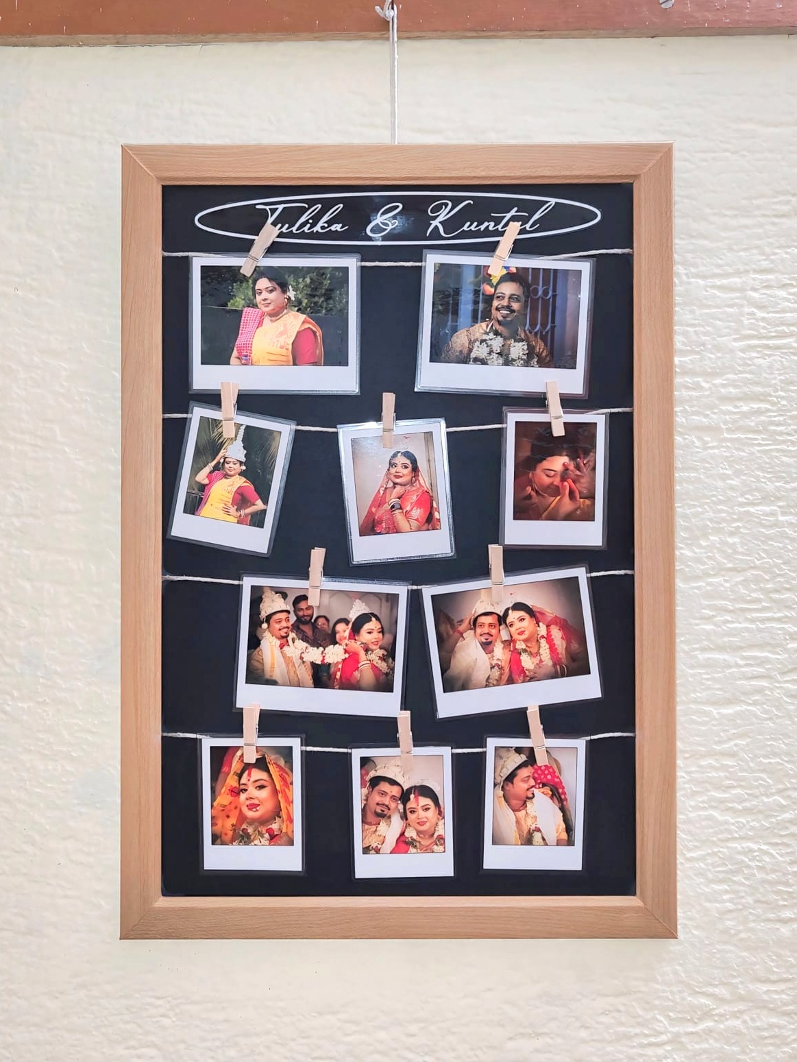 Wooden frame with the names “Tulika & Kuntal” featuring a string photo display of wedding memories, holding Polaroid-style prints clipped with mini clothespins.