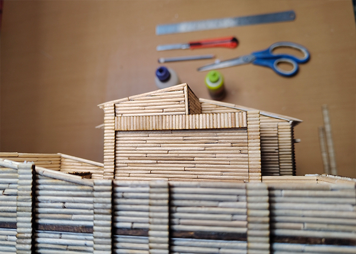 Close-up of roof section of toothpick model of Muragachha Government College with craft tools on the table.