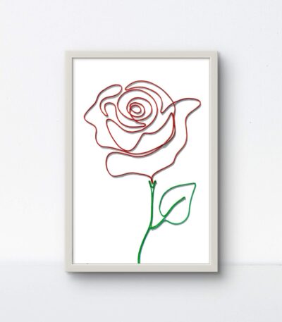 A handcrafted rose made of red and green rope, displayed in a clean white 9"x13" frame on a white background.