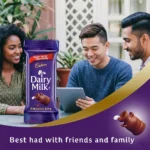 A promotional banner showing three friends smiling and looking at a digital tablet outdoors, juxtaposed with a Cadbury Dairy Milk chocolate bar on the left and a purple curve with text at the bottom.