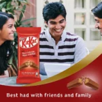 A promotional banner featuring a group of friends laughing together, with a large Nestlé KitKat bar on the left and a broken chocolate wafer finger illustration on a red and gold background curve at the bottom.