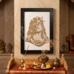 Upahar18 Adiyogi Shiva Rope Craft Portrait Frame mounted on a stone-textured mandir pillar above a festive pooja thali with a lit diya and incense smoke.