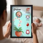 Close up real life shot of hands holding upahar18 personalized baby birth details classic photo frame design 011 with a blurred newborn baby sleeping in bed in the background