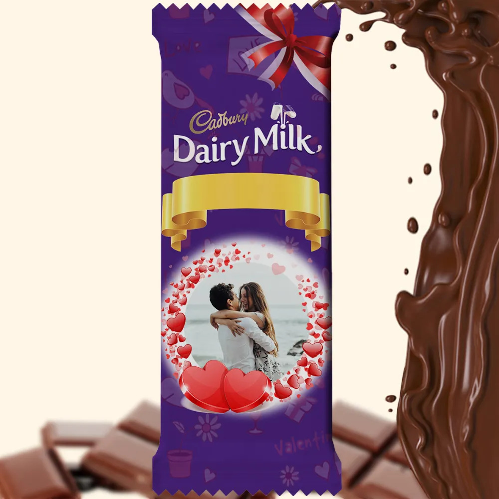 A personalized photo printed Cadbury Dairy Milk wrapper by upahar18, featuring a customized romantic couple photo surrounded by a heart-shaped frame and a gold ribbon design.