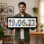 A smiling young man standing in a living room and holding a large classic black rectangular Upahar18 DATE Photo Frame displaying a custom-printed photo collage inside the date 19.06.22.