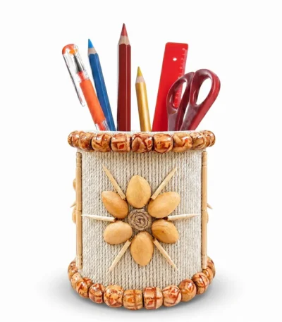 Studio shot on a pure white background of Upahar18 Handmade Eco-Friendly Rope Base Pen Stand filled with colourful writing utensils, scissors, and a red ruler, highlighting its vibrant red bead floral patterns, vertical jute lines, and sparkling mirror work.