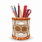 Studio shot of Upahar18 Handmade Eco-Friendly Rope Base Pen Stand against a clean white background. This artisanal desk organiser is packed with colorful pens, pencils, and office tools, showcasing its intricate seed flower emblem and terracotta-style wooden bead borders.