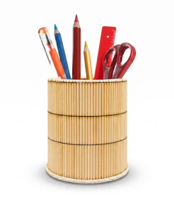 An isolated studio shot of a round handmade pen holder by Upahar18 on a plain white background. The holder is wrapped in brightly colored green, yellow, pink, and blue wooden sticks, filled with office stationery including pencils, a pen, and a pair of scissors.