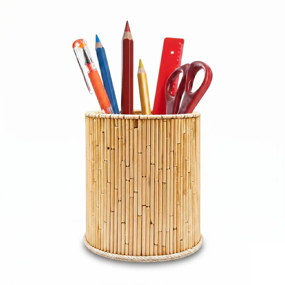 An isolated product shot of a round handmade pen stand by Upahar18 on a solid white background. The holder is covered tightly in slender, light brown natural wooden sticks and is filled with essential stationery items like pencils, a pen, and office scissors.