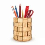 A front-facing studio shot of the Upahar18 handmade pen holder over a solid white background. The holder showcases a textured basket-weave look created with light tan wooden sticks, filled with various office stationery items like color pencils and scissors.
