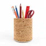 A multi-angle product feature of the Upahar18 handmade textured pen stand. The upper circular image presents a birds-eye view inside the stand showing a spiral-coiled rope base encircled by natural wooden sticks, while the lower panel displays two matching woven pen holders side-by-side on a white backdrop.