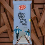 A pre-designed light blue chocolate wrapper featuring a soulful Bengali Quote that says "Hatate Chai Koyek Pa Tor Sathei." This Romantic themed KitKat design showcases a minimalist couple illustration walking on a railway track, capturing a nostalgic and sweet moment.