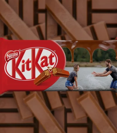 A horizontally designed upahar18 customized red kitkat chocolate bar package featuring a personalized photo printed image of a couple playing in the water next to a melted chocolate stream.