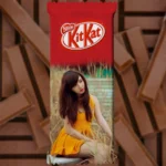 A vertical upahar18 personalized chocolate wrapper for a kitkat bar, showing a customized photo printed portrait of a woman in a yellow dress sitting among tall dry grass.