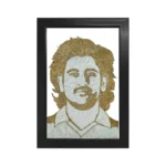 A handmade rope craft portrait of legendary cricketer MS Dhoni with his iconic long hair style, crafted using textured brown jute and white fibers in a sleek black frame.