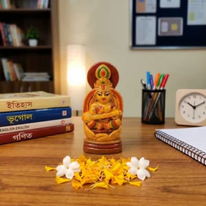 Handcrafted upahar18 Terracotta Maa Saraswati idol placed on a wooden study table next to notebooks, texts, and fresh flowers, made in Krishnanagar.