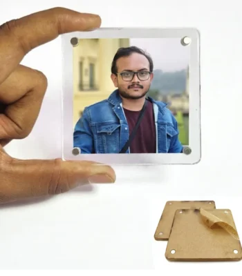 A person holding a square-shaped borderless acrylic magnetic photo frame showing a customized portrait of a man in a denim jacket and glasses, with a pair of protective brown kraft paper layers beside it by upahar18.