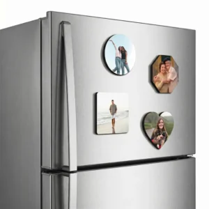A side angle lifestyle view of a metallic double-door refrigerator highlighting a combo set of four different shaped personalized MDF photo printed fridge magnets including a round, octagon, square, and heart shape, showcasing the thick premium wooden edge profile and a strong flat hold against the metallic surface by upahar18.
