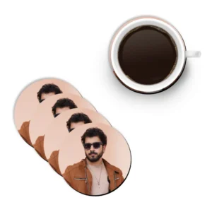 A flat lay mockup showing a white ceramic mug filled with hot black coffee next to a diagonal stack of four round MDF coasters from upahar18 printed with a personalized custom photo of a man in sunglasses.