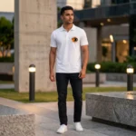 A male model standing outdoors wearing a white polo collar T-Shirt from upahar18 with a circular custom photo logo printed on the left chest.