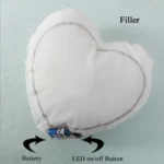 A technical product layout displaying the inner heart-shaped cushion filler with an attached battery link and LED switch by upahar18.