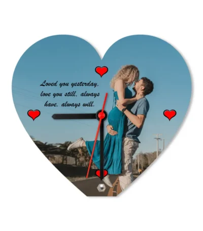 A studio front view of a white-background isolated heart-shaped upahar18 Table clock printed with a custom photo of a couple and a romantic message.