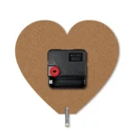 The back view of a heart-shaped upahar18 MDF clock showcasing its raw brown fiberboard texture, black quartz movement engine, and a silver metal support stand.