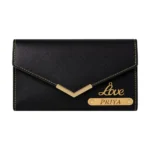 A studio-lit studio shot of an envelope-style black faux Leather Wallet for women from upahar18, featuring a golden V-shaped accent, an elegant "Love" charm, and a custom name strip printed with "PRIYA" against a plain background.