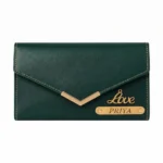 A studio shot from a flat front angle of a closed envelope clutch style emerald green faux Leather Wallet for women from upahar18, showing a metallic gold V-accent on the front flap, a polished cursive 'Love' charm, and a custom name strip printed with PRIYA against a plain white background.
