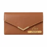 A studio shot from a flat front angle of a closed envelope clutch style light brown faux Leather Wallet for women from upahar18, showing a metallic gold V-accent on the front flap, a polished cursive 'Love' charm, and a custom name strip printed with PRIYA against a plain white background.