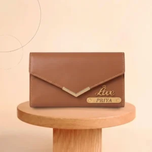 A professional lifestyle product photograph of a closed light brown envelope-style faux Leather Wallet from upahar18, standing upright on a round wooden log slice placeholder, highlighting a personalized gold V-trim, a cursive 'Love' charm, and a custom name plate printed with PRIYA, matching the style of a custom men Wallet.