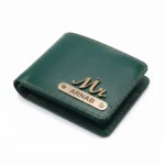 A close-up studio shot from an isometric angle of a closed olive green faux Leather Wallet for men from upahar18, featuring distinct yellow border stitching, a metallic 'Mr.' charm, and a custom name metal plate printed with ARNAB over a clean white background.