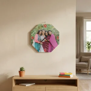 An octagon-shaped MDF clock from upahar18 hanging on a beige living room wall above a wooden TV console cabinet, featuring a colorful printed custom photo of four female friends.