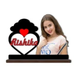 A high-definition printed MDF cutout standee by upahar18 featuring a personalized custom photo of a smiling woman next to a heart frame with a black cloud silhouette on top and the name "Rishika" printed inside, isolated on a white background.