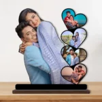 A vibrant personalized custom photo printed MDF cutout standee by upahar18 of a romantic couple's heart collage, beautifully displayed on a premium wooden tabletop surface against a neutral wall backdrop.