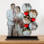 A high-quality printed MDF cutout standee by upahar18 featuring a personalized custom photo collage with a main cutout of a wedding couple alongside five hexagon-shaped photo slots decorated with red hearts, placed on a wooden tabletop.