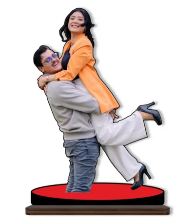A joyful personalized custom photo printed MDF cutout standee from upahar18 showing a cheerful man lifting a woman wearing a bright orange blazer and white pants, isolated on a plain white background.