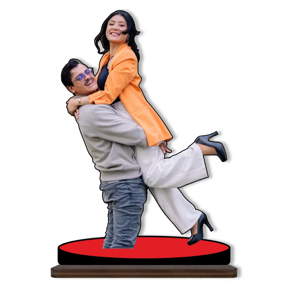 A joyful personalized custom photo printed MDF cutout standee from upahar18 showing a cheerful man lifting a woman wearing a bright orange blazer and white pants, isolated on a plain white background.