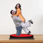 A vibrant personalized custom photo printed MDF cutout standee by upahar18 featuring a happy couple, beautifully displayed on a premium wooden tabletop against a clean neutral wall background.