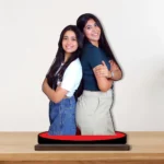 A vibrant personalized custom photo printed MDF cutout standee by upahar18 of two happy female friends, displayed beautifully on a premium wooden tabletop against a plain wall.