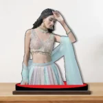 A gorgeous printed MDF cutout standee by upahar18 showcasing a personalized custom photo of a woman in a glamorous traditional pastel lehenga choli pose, placed on a wooden desk.