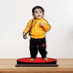 A vibrant personalized custom photo printed MDF cutout standee by upahar18 of a cute baby, elegantly displayed on a premium wooden tabletop surface against a clean studio wall backdrop.