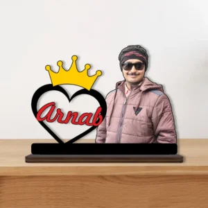 A vibrant personalized custom photo printed MDF cutout standee by upahar18 of a royal crown name and photo design, displayed elegantly on a smooth wooden tabletop surface against a neutral background.